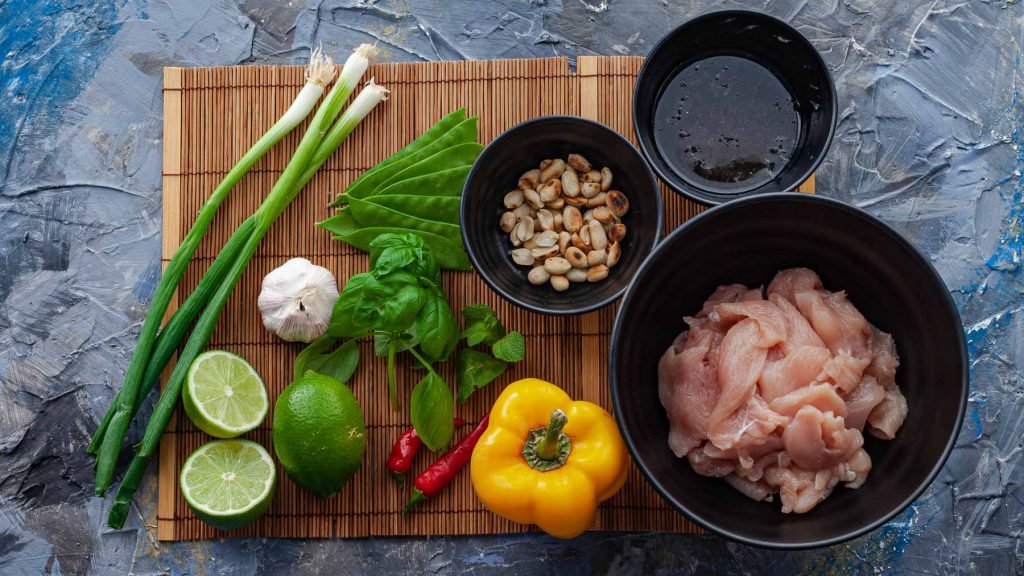 Thai Basil Chicken ingredients: green onion, lime, basil, mint, red chili, peppers, snow peas, peanuts, chicken, sweet, sour, spicy, salty sauce.